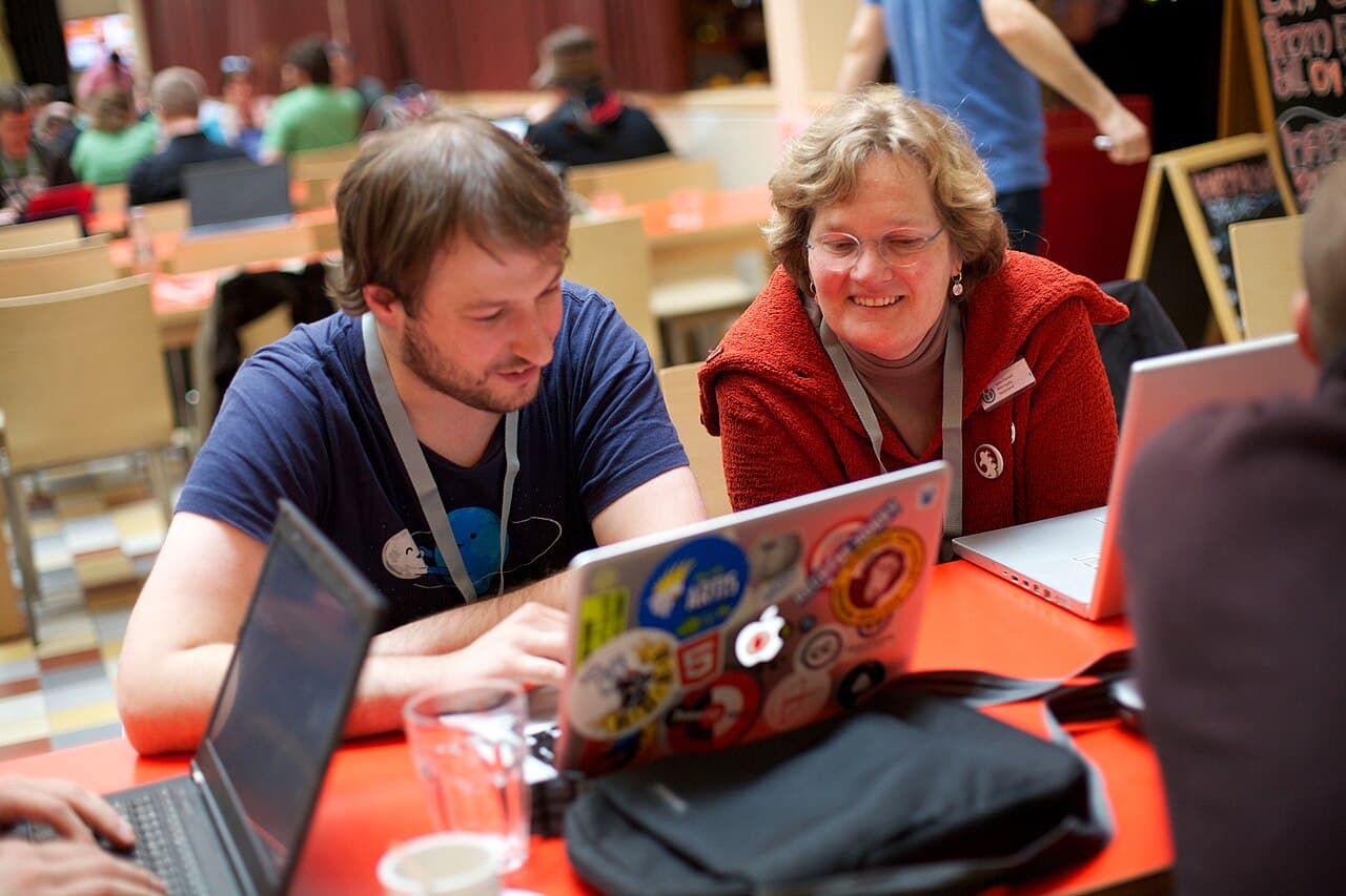 Open-source developers collaborating on laptops at the Wikimedia Hackathon, representing human review and accountability in software contributions