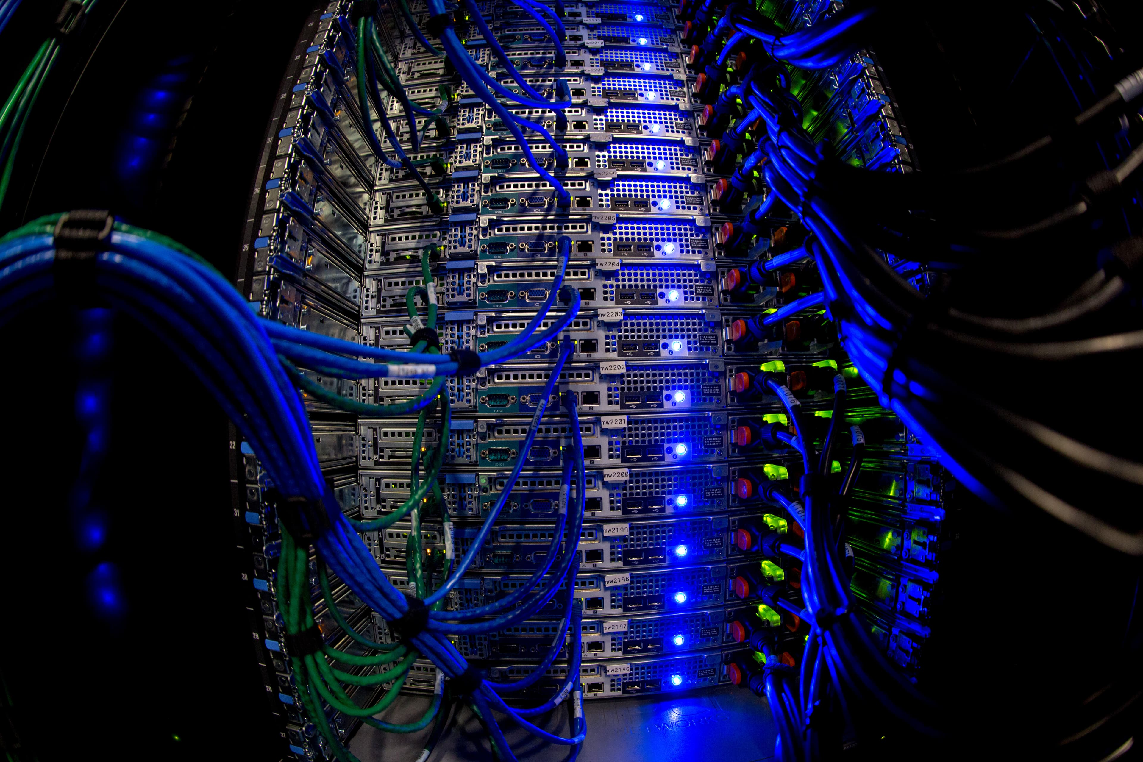 Rows of illuminated server racks and network cables in a data center, representing the AI infrastructure spending exposed to rising financing costs