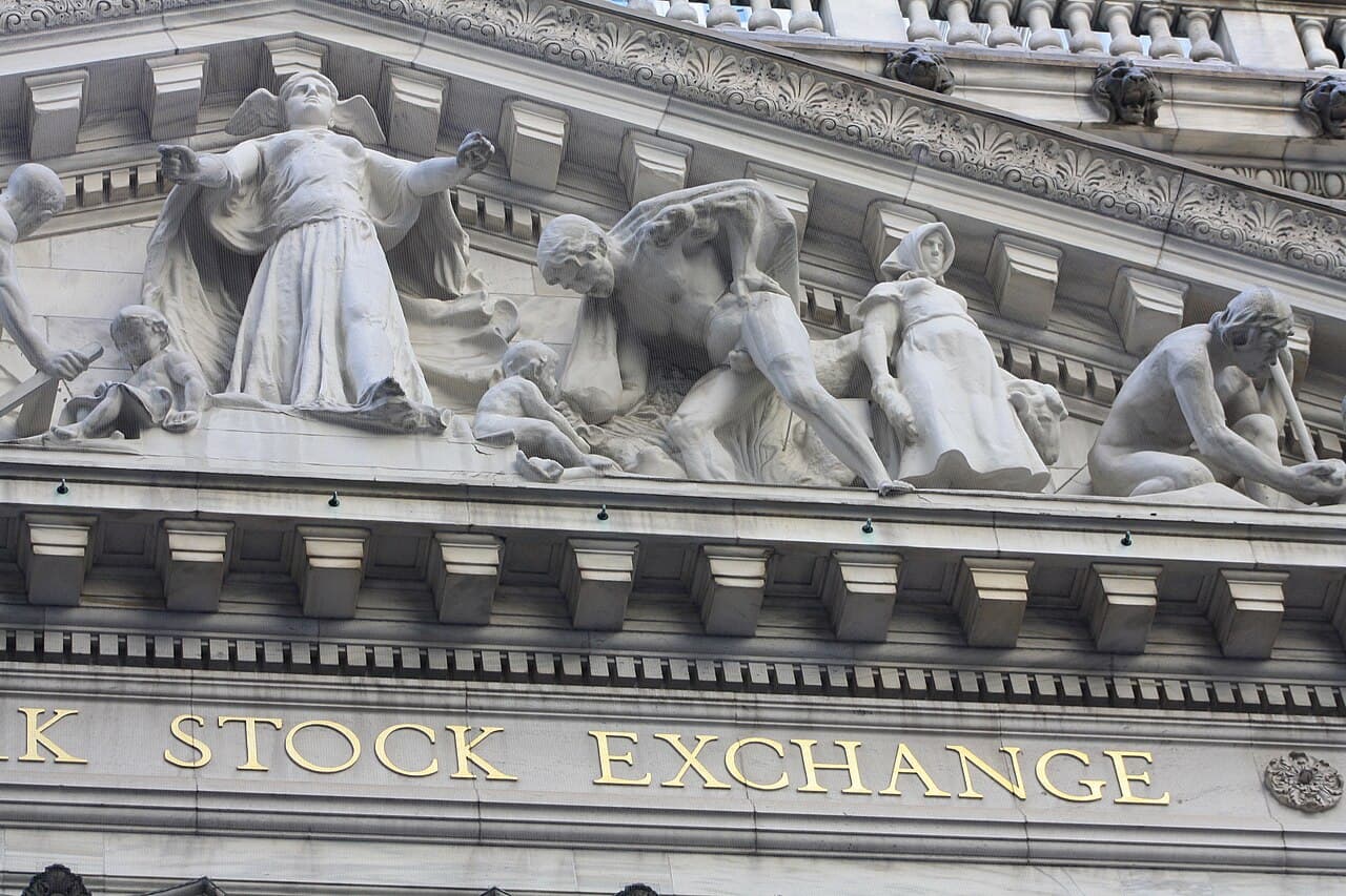 Stone figures above the New York Stock Exchange facade, representing a split session with index, banking and energy momentum